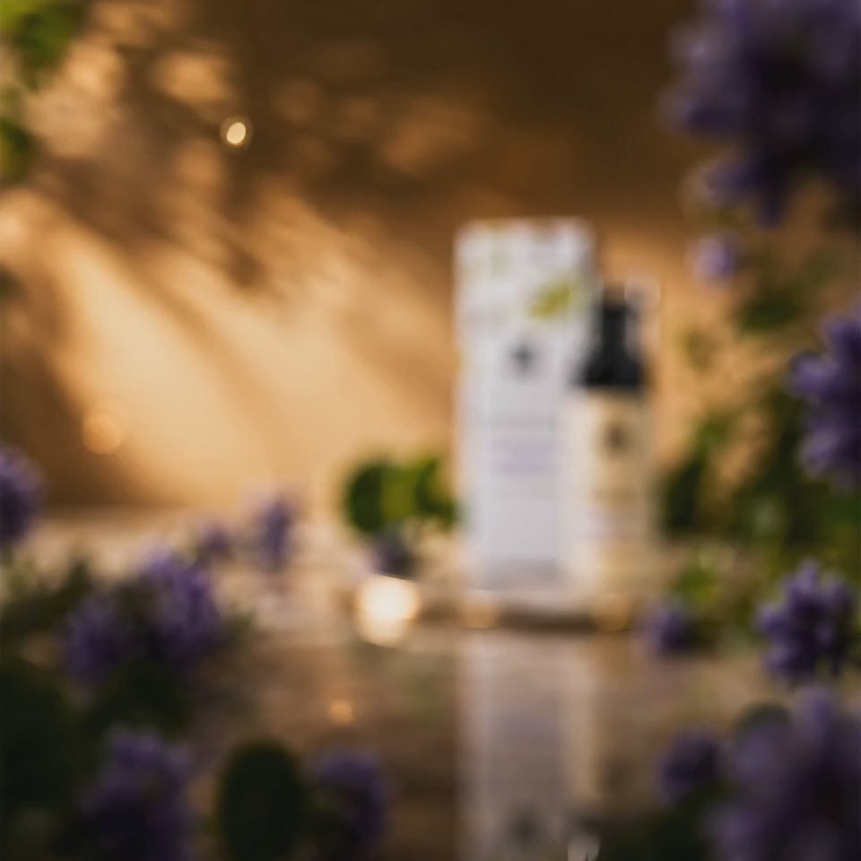 "Product video for DEHAZ Retinol & Centella Renewing Cream: close-up shots of the cream's texture and pump dispenser, styled with Centella Asiatica leaves and purple flowering botanicals on a marble and gold surface, jar and box rotating to display label, ending on a lifestyle shot of a model with smooth, radiant-looking skin."